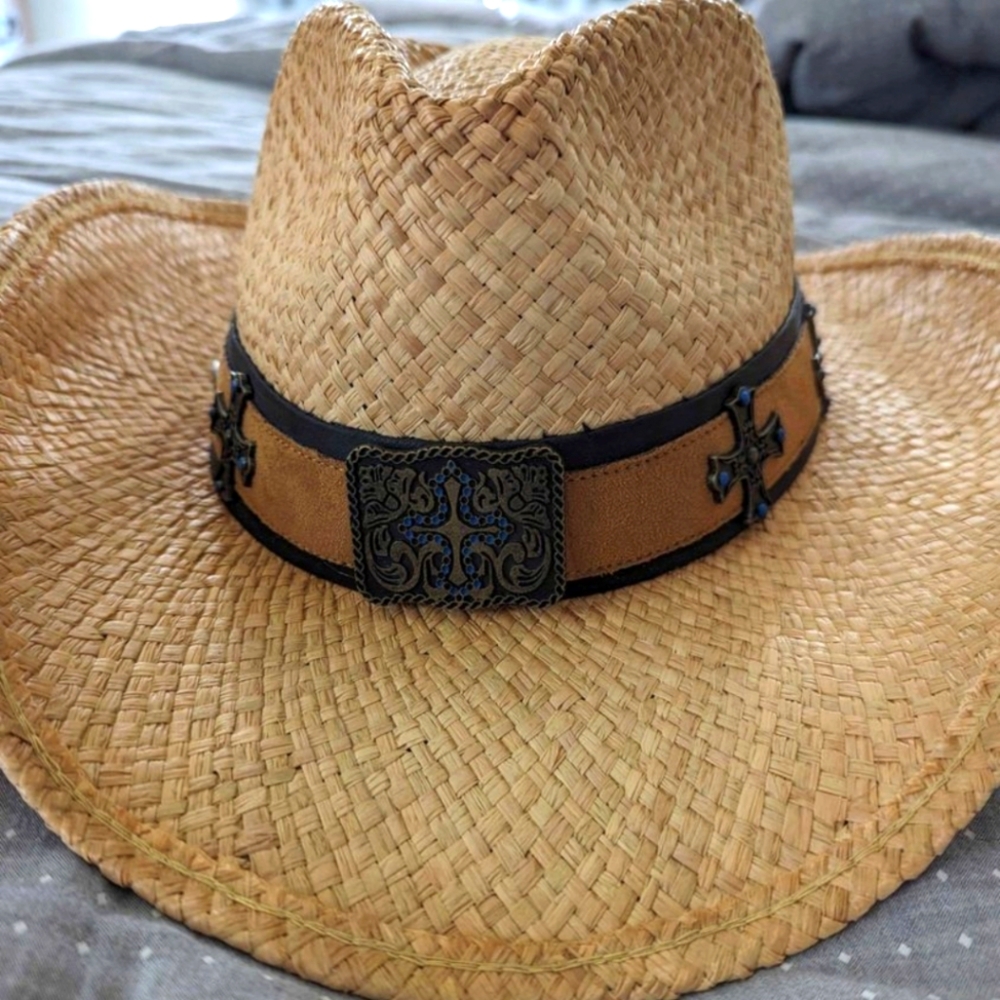 Straw cowboy hat with leather strap and metal details.
